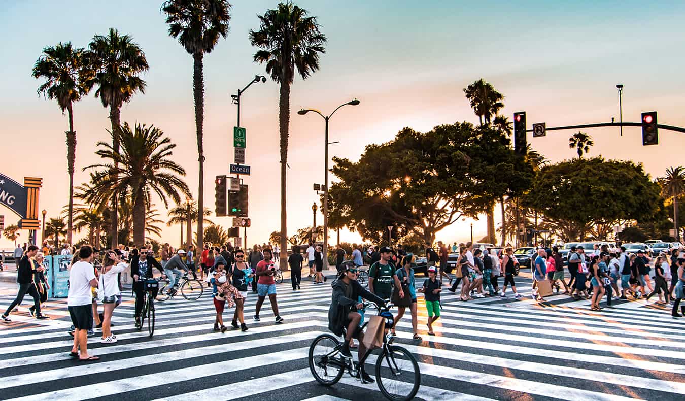 A busy Los Angeles crosswalk full of people during sunset