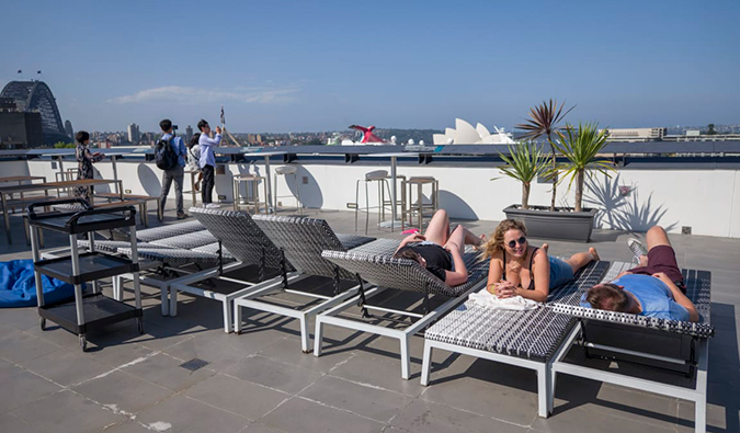 澳大利亚悉尼，悉尼港青年旅社的屋顶露台上，人们躺在躺椅上晒日光浴