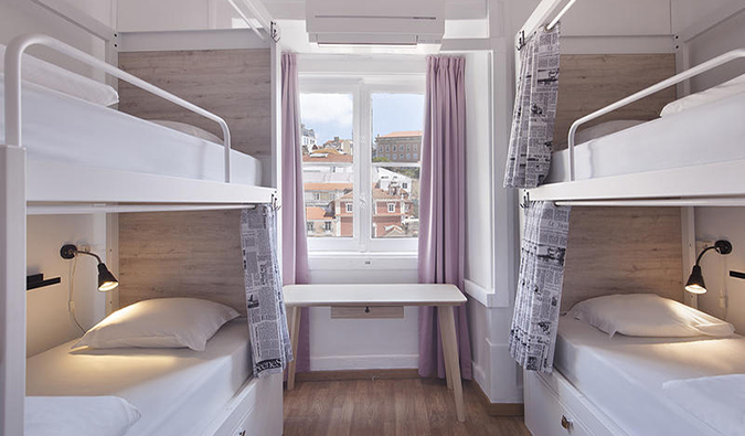 Modern dorm room with bunk beds and window looking out over rooftops of Lisbon at Good Morning Solo Traveller Hostel, Lisbon