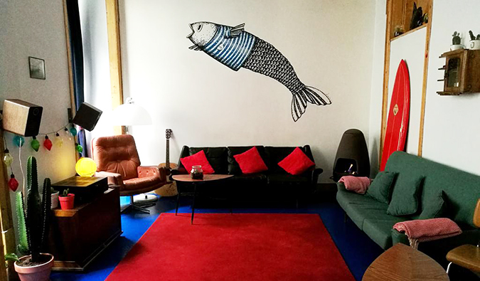 Common area with mix of couches and a large fish painted on the wall at Goodnight Hostel, Lisbon