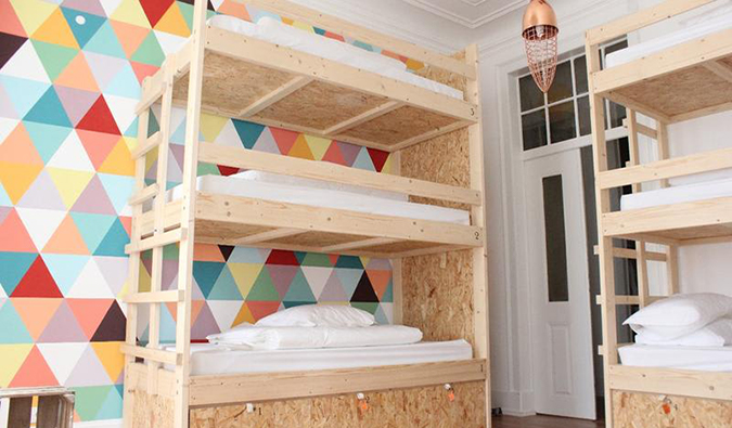 3 bed wooden bunk beds in colorful dorm room at Lookout! Lisbon Hostel