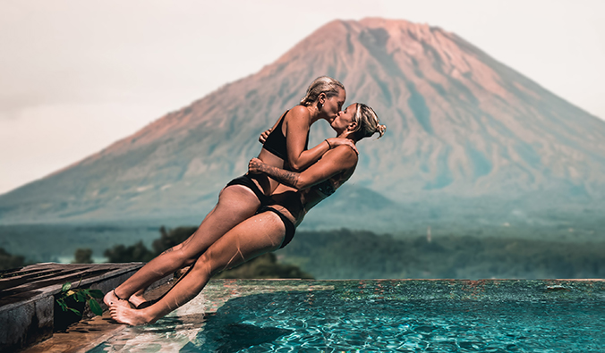 夏洛特和娜塔莉在巴厘岛一座火山前的游泳池里潜水