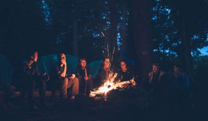 一群朋友和旅行者晚上坐在火炉边