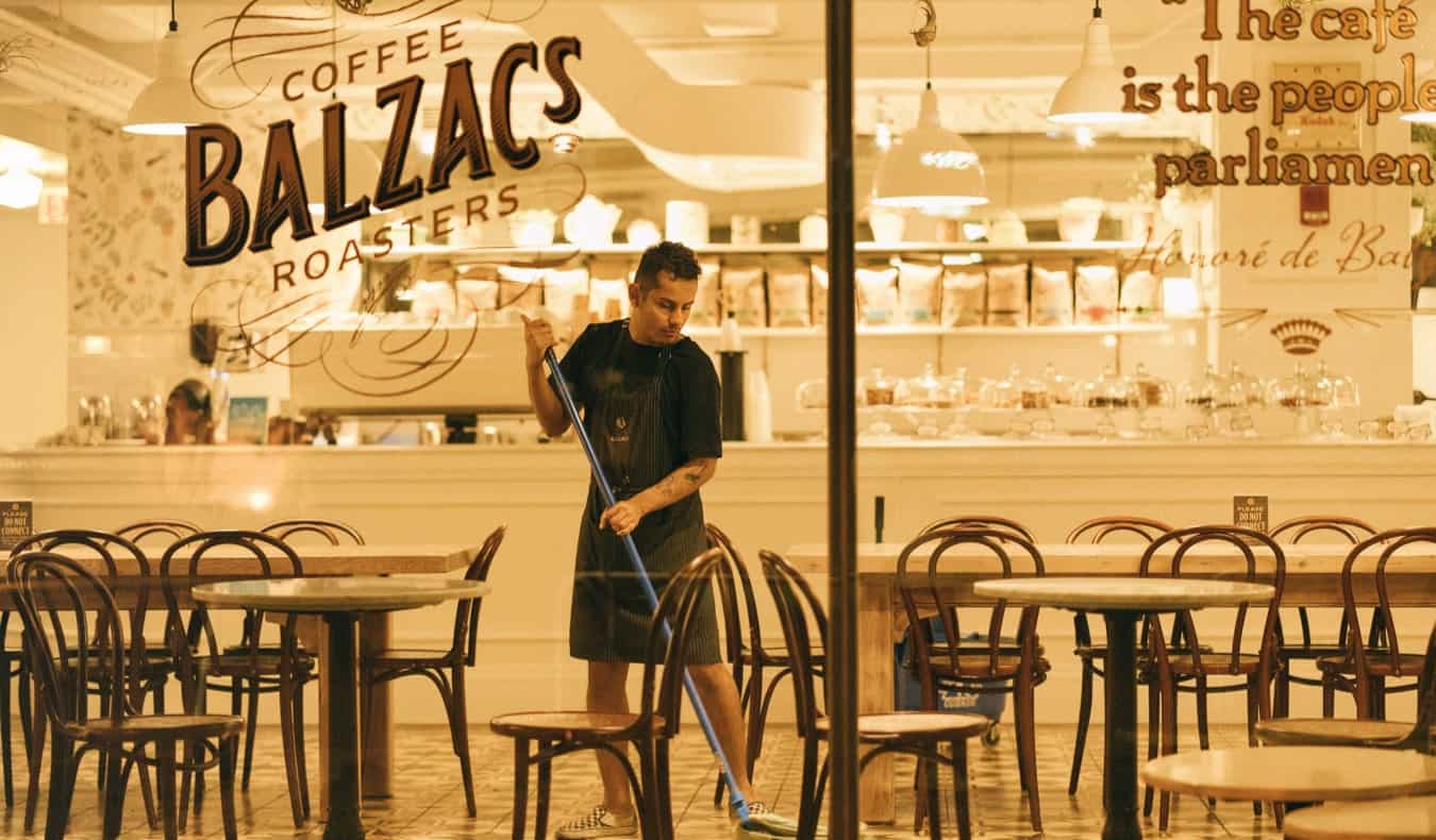 一名年轻的男性工人晚上在咖啡馆和餐厅拖地