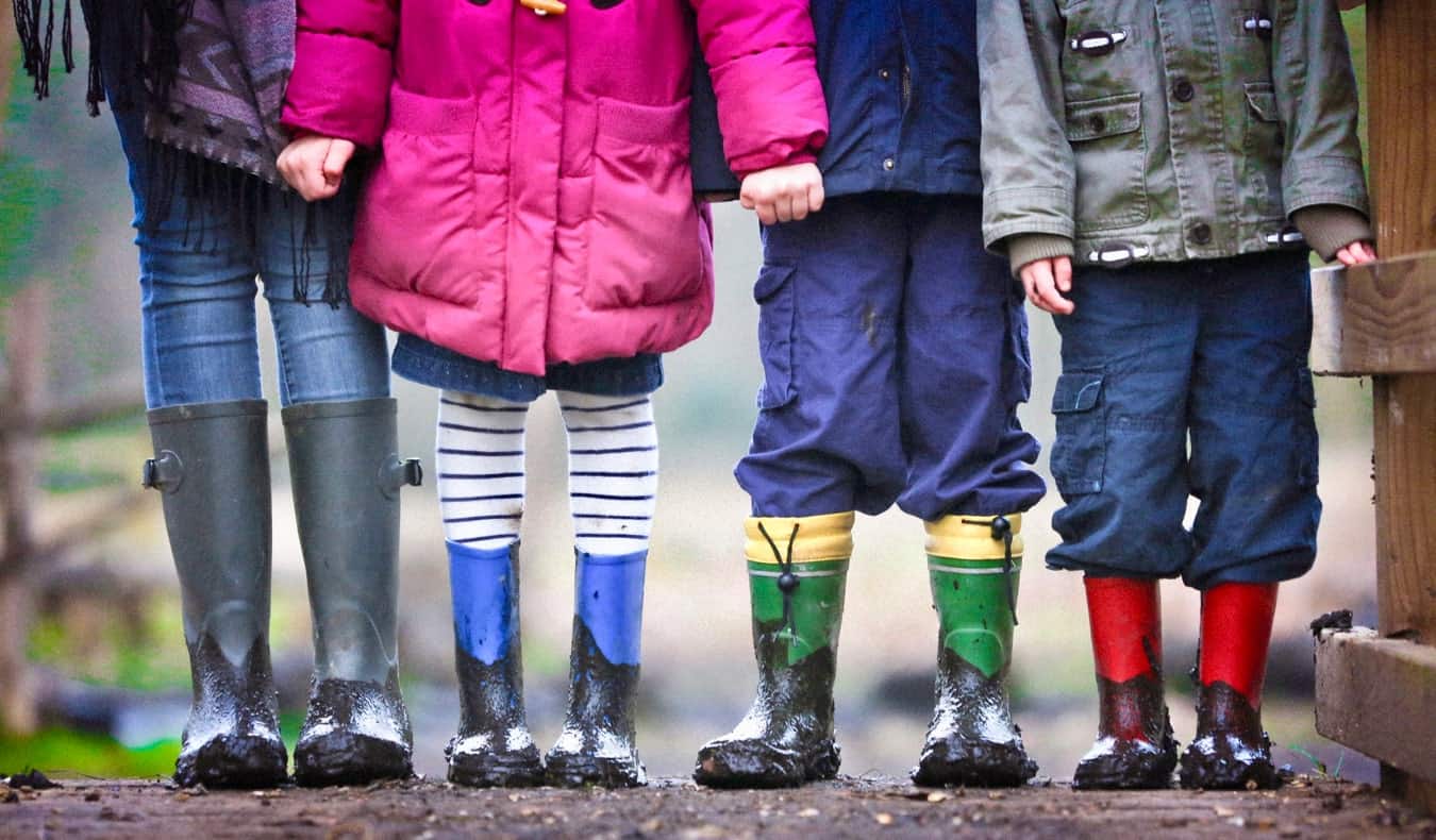 一个互惠生和穿着雨靴的孩子们站在泥地里