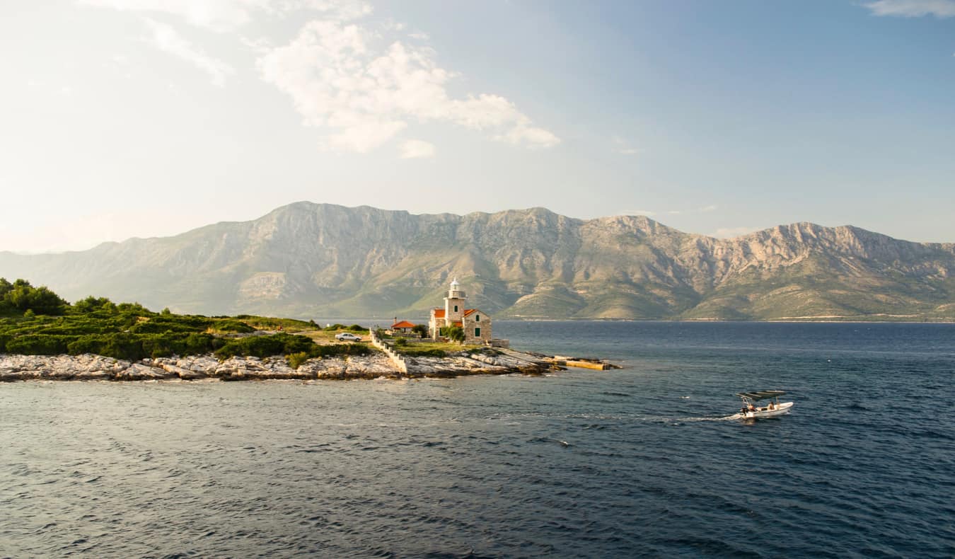 An isolated building on the coast of Hvar, Croatia with mountains in the background