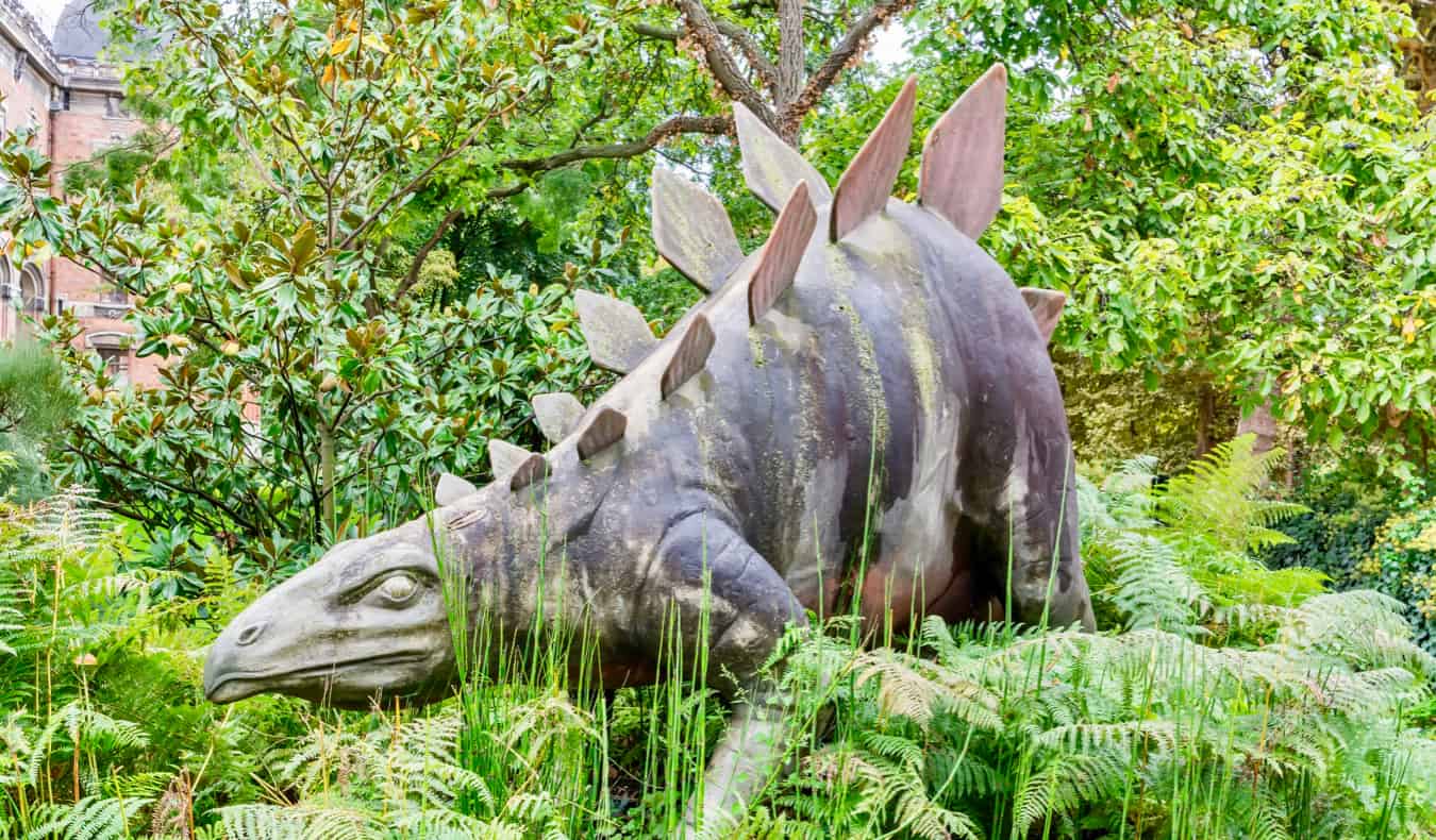法国巴黎，高高的草丛中的恐龙雕像