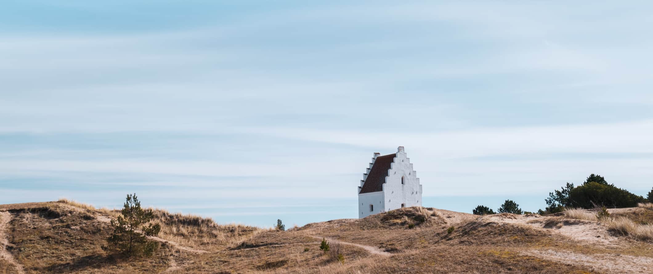 一座白色的小教堂，坐落在丹麦日德兰半岛崎岖、狂风肆虐的海岸上