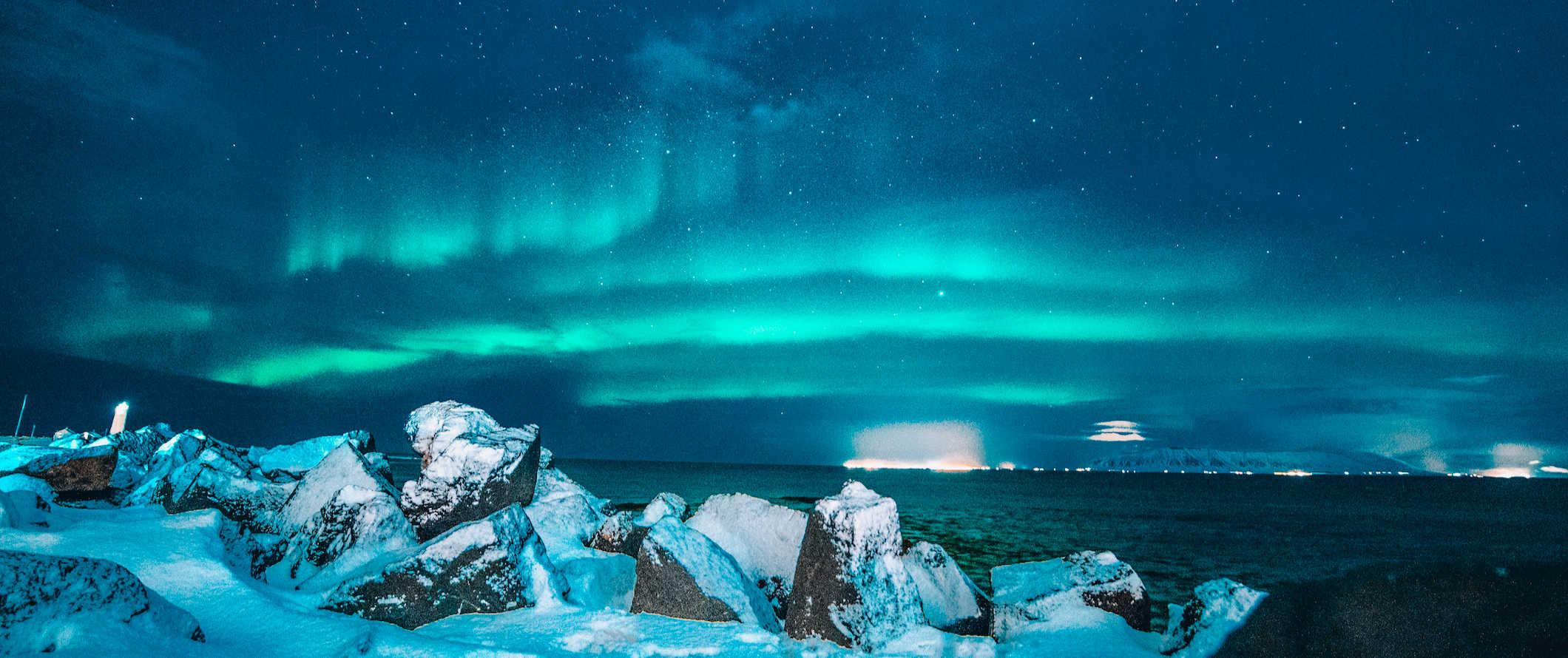 The Northern Lights shining bright green over a snowy Icelandic landscape