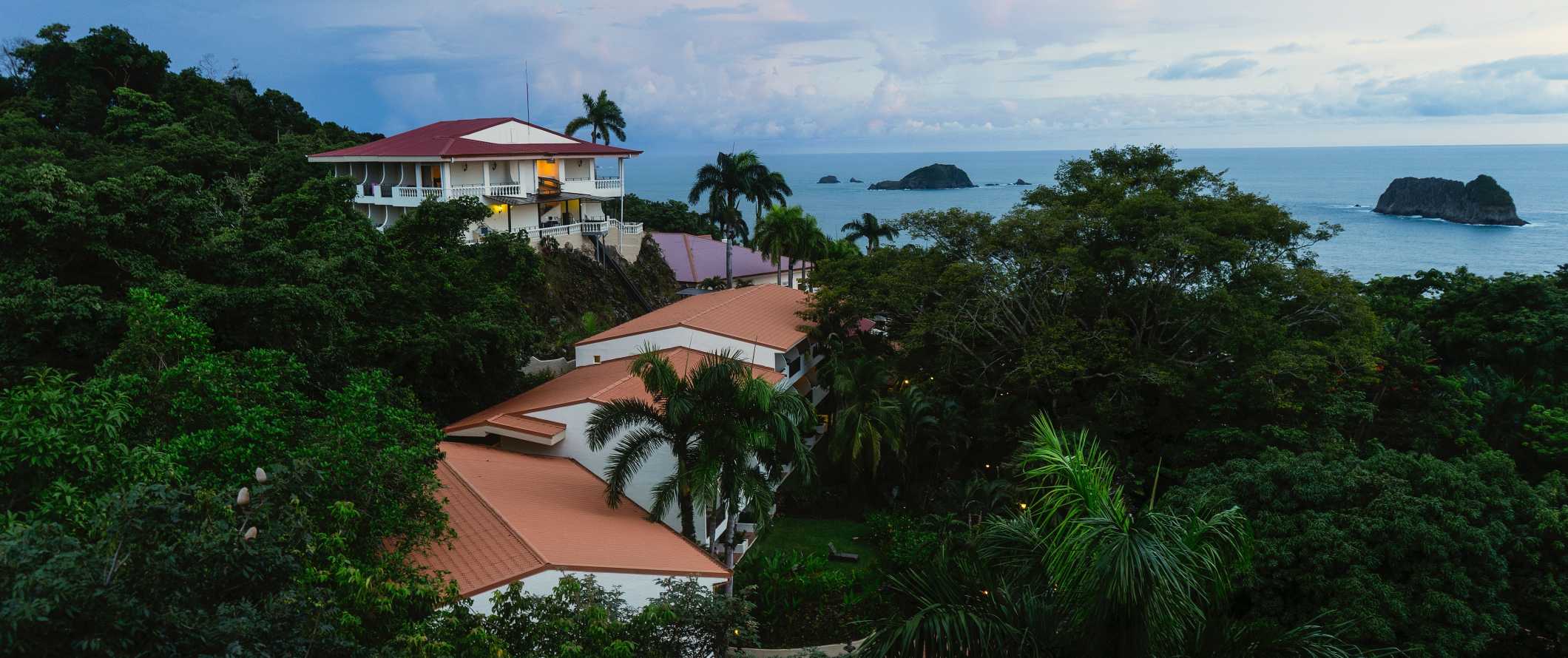 哥斯达黎加曼努埃尔安东尼奥的小度假村和酒店建筑坐落在热带雨林中，背景是海洋