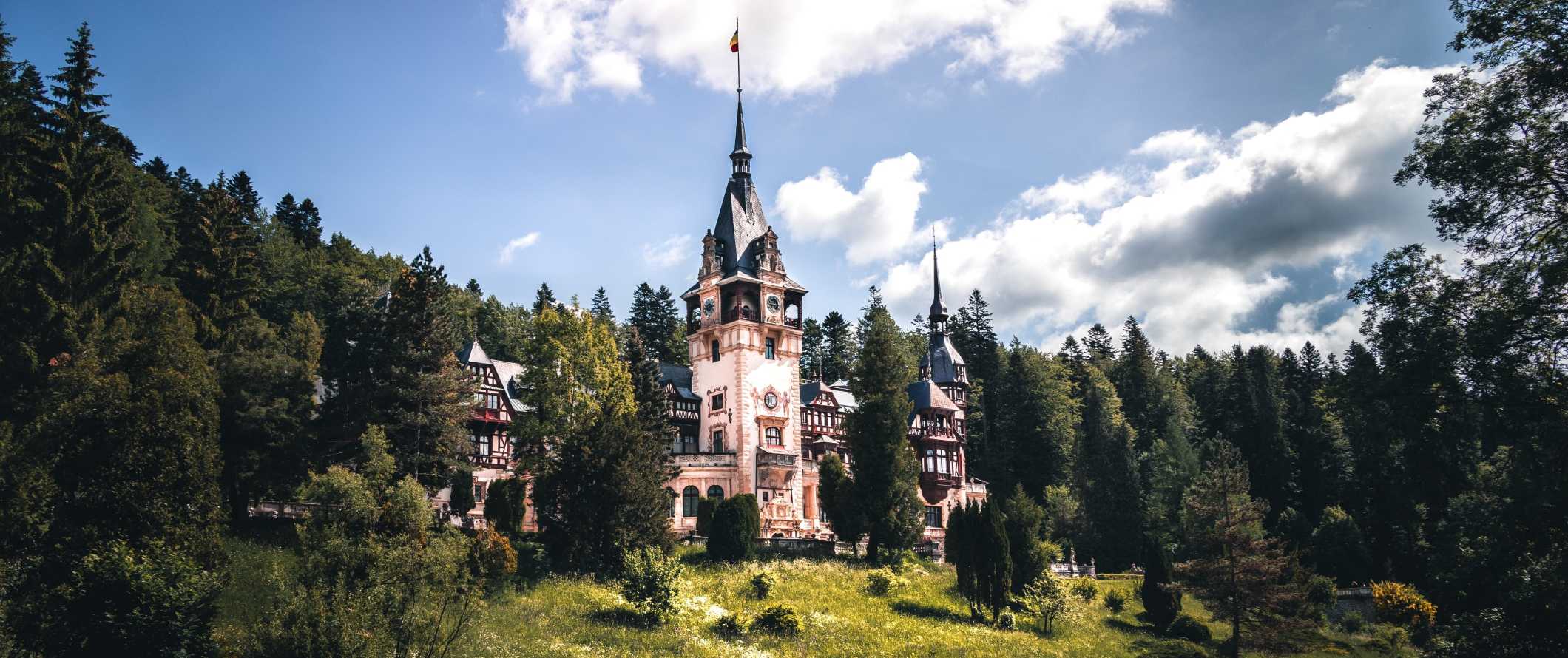 The fairytale-esque Peles Castle, surrounded by trees, in Romania.