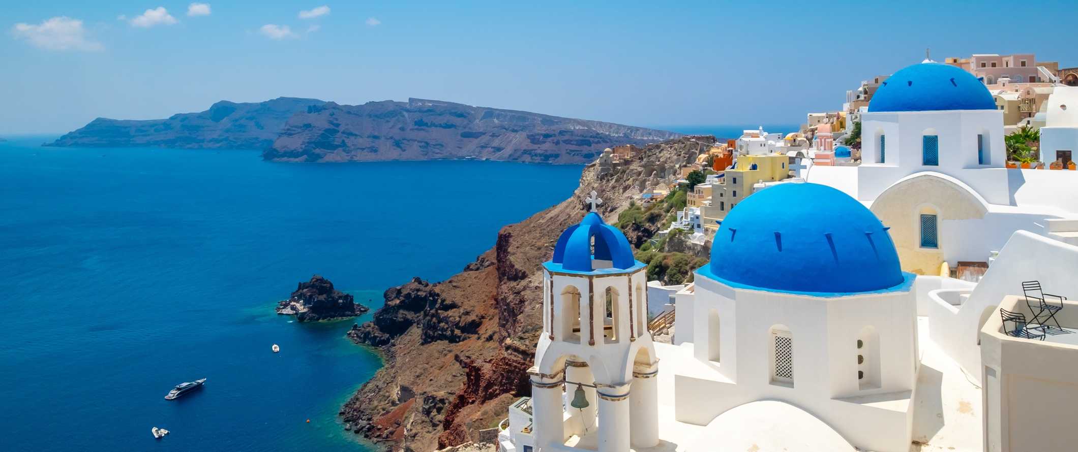 White-washed buildings with blue domed roofs overlooking the Mediterranean in Santorini, Greece