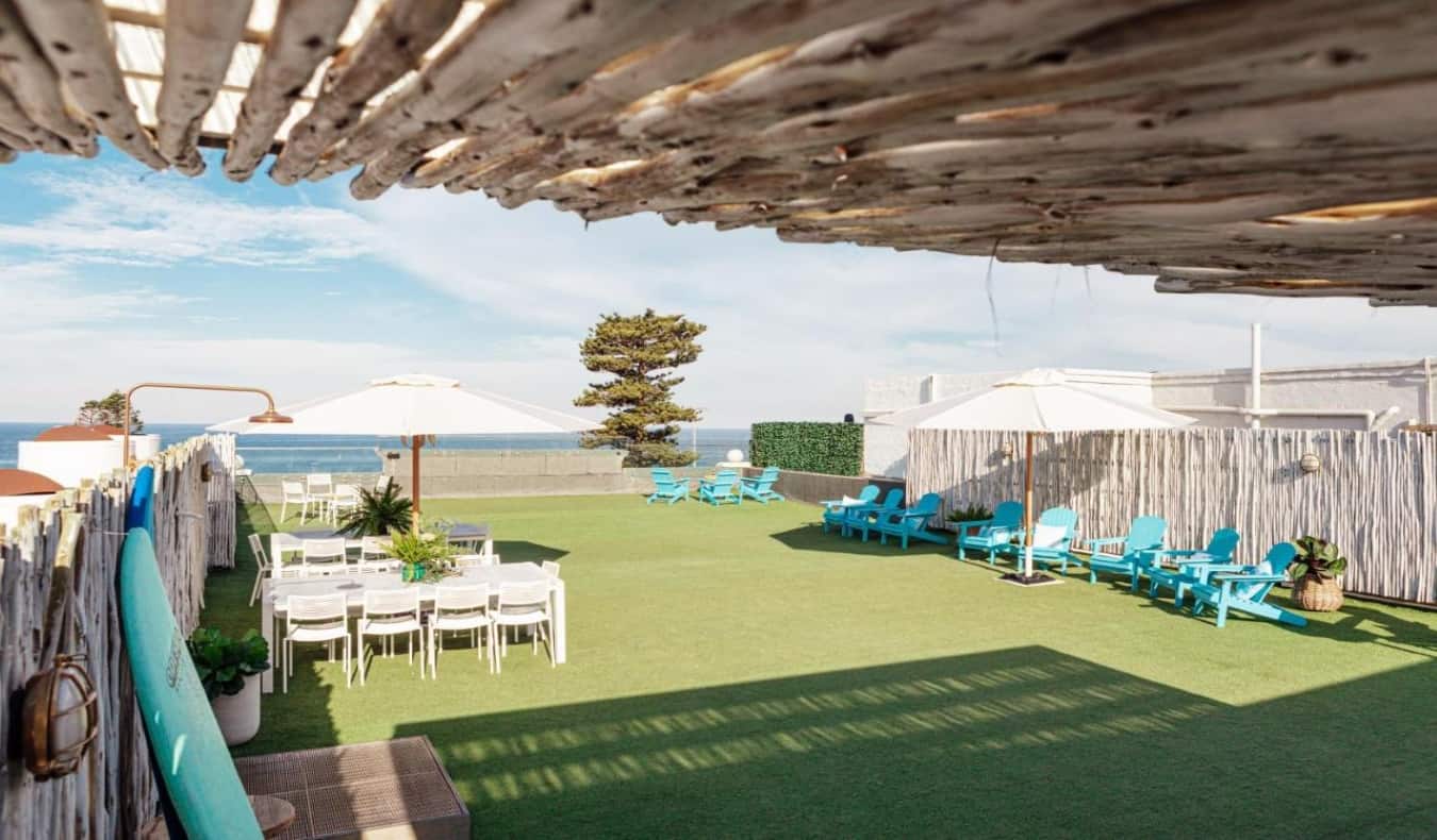 屋顶上有草坪椅、雨伞和桌子，醒醒吧!邦迪海滩旅馆