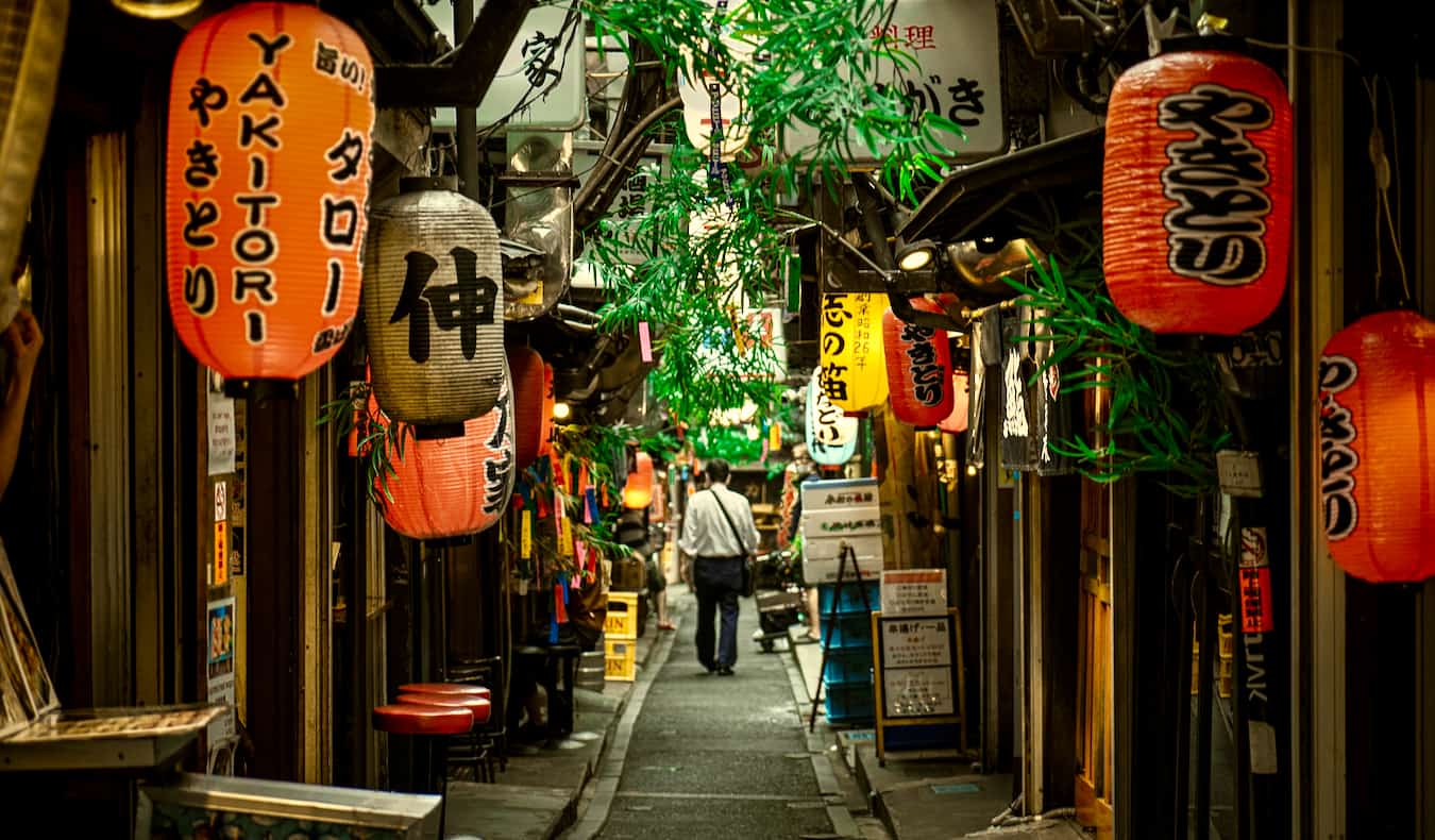 一位旅行者在日本东京新宿地区一条昏暗狭窄的小巷里探险