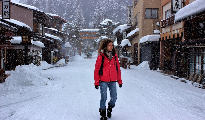 冬天，一位独自行走在日本雪地上的女性旅行者