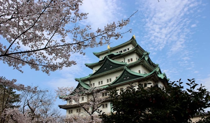 一座传统的日本城堡，周围环绕着树木和明亮的蓝天