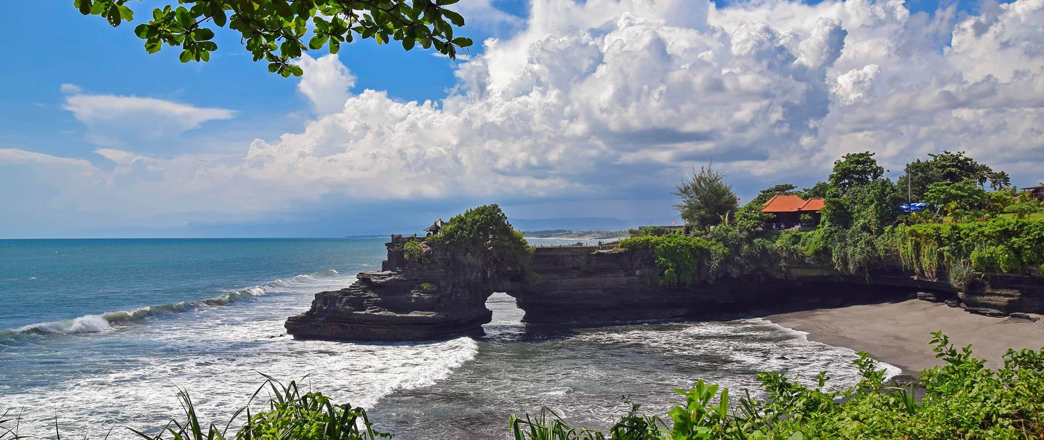 A rugged beach in Bali, Indonesia surrounded by green trees on a sunny day