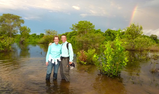 An older couple traveling in a developing country with a rainbow in the background