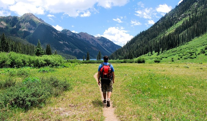 a backpacker hiking in beautiful meadow surrounded by mountains