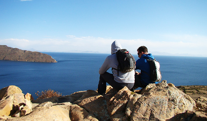 两个旅行者坐在海边的岩石上