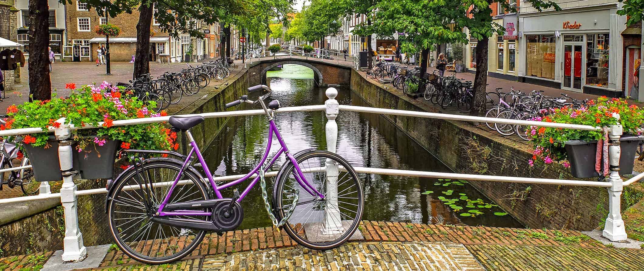 a view of a canal in the Netherlands with a bike leaning against a bridge