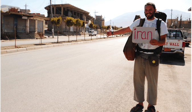 一个背包客举着牌子独自在伊拉克搭便车