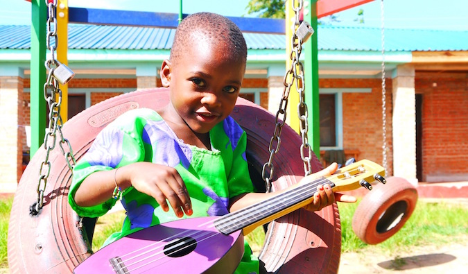 一个穿着彩色衣服的非洲小孩在弹小吉他