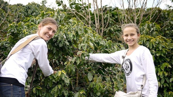 一个女人和一个女孩微笑着在国外志愿采摘水果