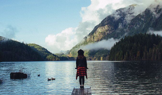 一个女人站在码头上，俯瞰山上的湖泊