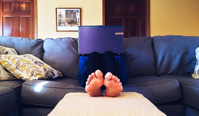 一个长沙发的人有脚的脚往照相机障碍阻塞由膝上型计算机