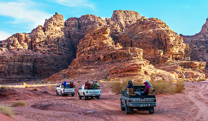 三辆卡车与人们坐在后面穿过约旦