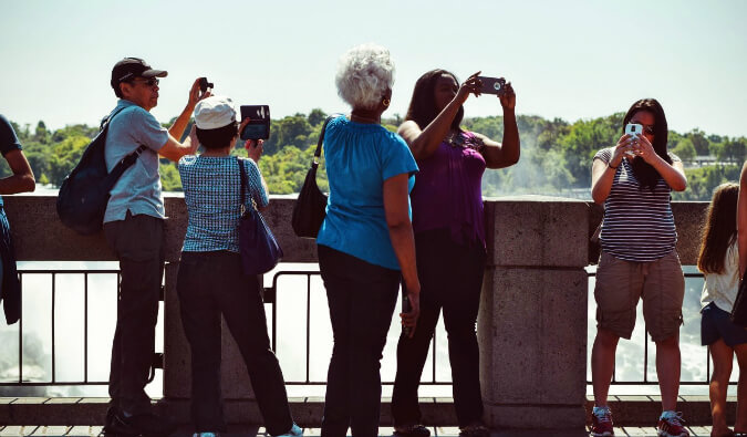 5个人在桥上用手机和相机拍照