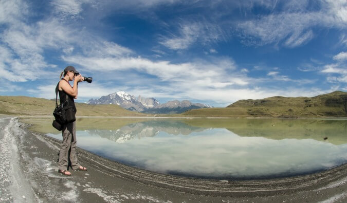 拍与她的dslr照相机的妇女一张照片在湖反射了