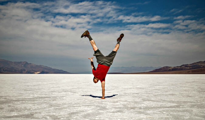 一个人站在空地上，地上积着雪，一只手倒立着