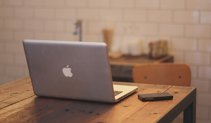 Mac书专业人在一台手机旁边的一张木桌上打开