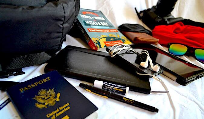 护照、旅行指南、耳机、笔、唇膏和其他准备打包的物品。