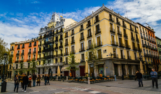 马德里的街景，5层黄色建筑的街角，人们站在街上，走在街上