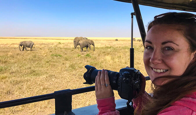 拿着一个dslr照相机的海伦准备拍摄一些大象的照片在野外