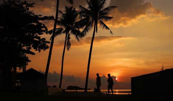日落剪影的两个人走在海滩上在泰国兰塔岛