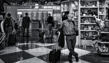 一个独奏旅客的黑白照片在看他的电话的机场