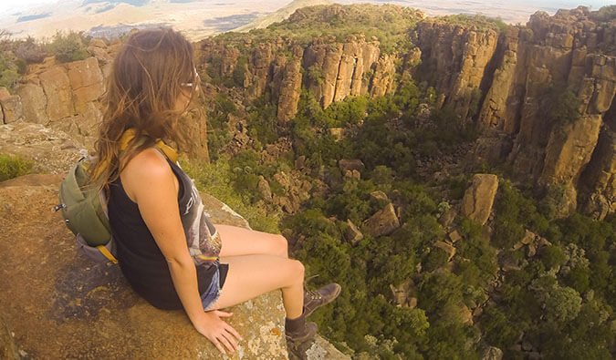 克里斯汀·阿迪斯(Kristin Addis)坐在南非的一块岩石上，她的腿悬在岩石边缘