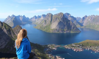 女旅行者坐在山顶凝视着海外的大海