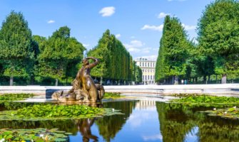 在奥地利维也纳的一座宫殿附近，一个平静的喷泉反射着树木