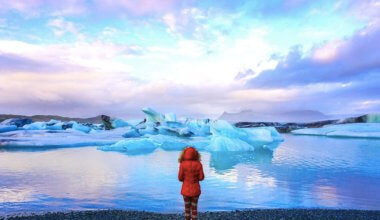 一件读外套的独奏女性旅行者在冰川盐水湖在冰岛