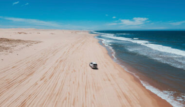 在澳大利亚一个开阔的海滩上，一辆四轮驱动汽车在沙滩上行驶