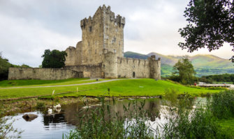 一座爱尔兰城堡，坐落在宁静的湖面上，映衬着青山