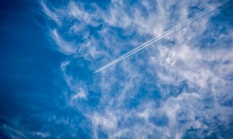 一架商用飞机高高在上，切割着云朵和蔚蓝的天空