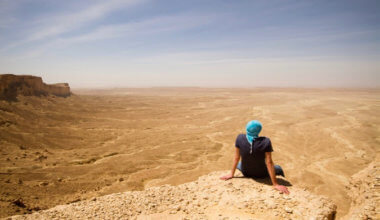 独奏旅客坐一个峭壁在沙特阿拉伯的沙漠