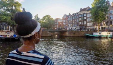 Senitra，一个独自的黑人女性旅行者在欧洲的一条运河附近摆姿势