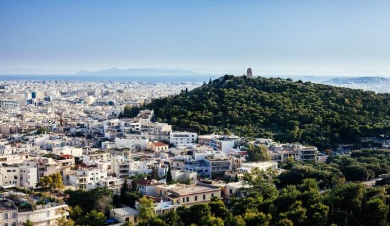 雅典的城市景观，白色的建筑和巨大的森林山丘